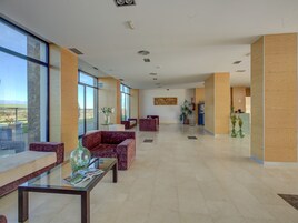 Un vestíbulo amplio con ventanas grandes, asientos cómodos y una zona de recepción.