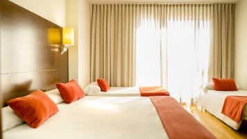 Habitación de hotel con dos camas, cabecero de madera, lámpara de pared y un ventanal con cortinas.