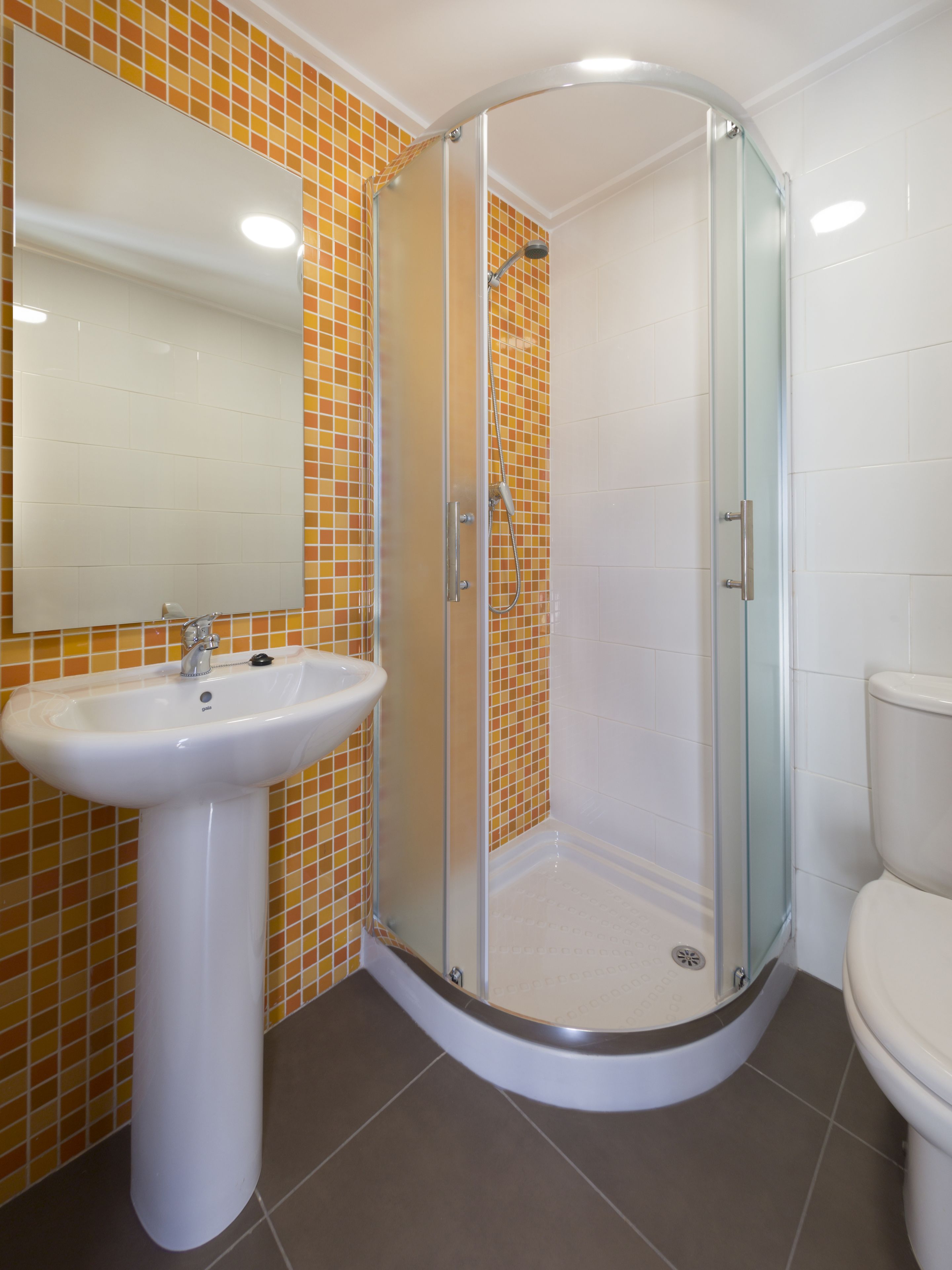 A bathroom with a glass-enclosed shower, a white sink, and a toilet.