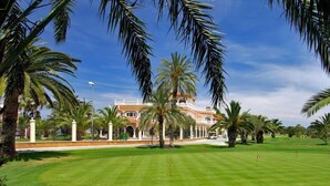 Ein gepflegter Golfplatz mit einem großen, verzierten Gebäude im Hintergrund.