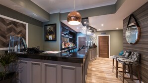 Eine moderne Bar mit einer zentralen Barinsel, Barhocker, einer Pendelleuchte und einem Spiegel an der Wand.