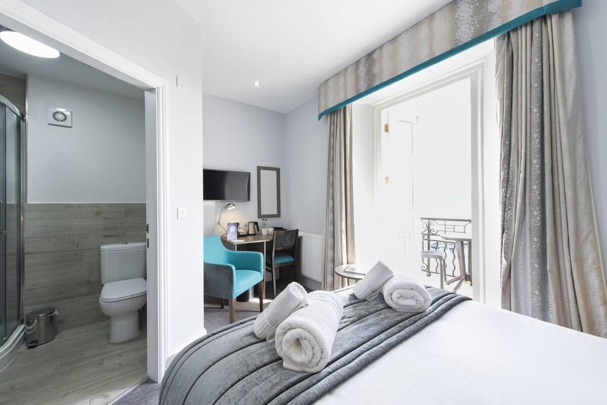 Une chambre d’hôtel équipée d’un lit, d’un bureau, d’une chaise, d’une télévision et d’une salle de bain.