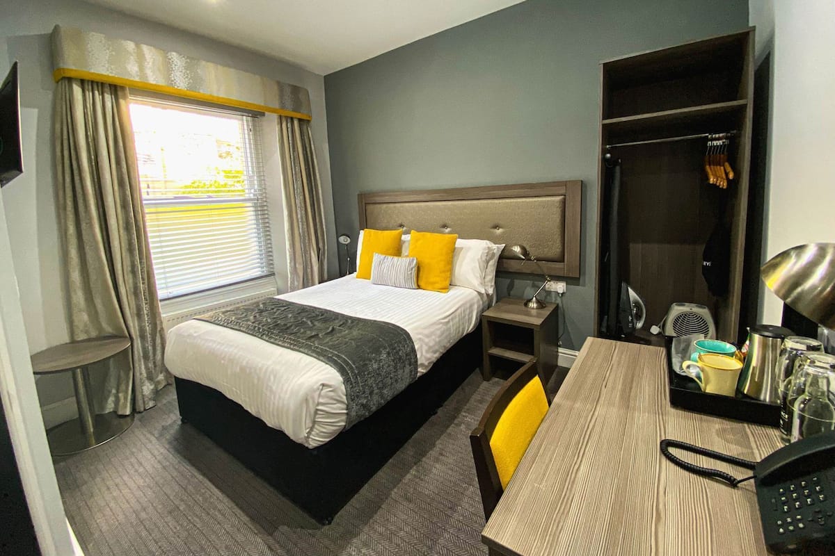 Une chambre d’hôtel comprenant un lit, une table de chevet, une chaise, un bureau et une armoire.
