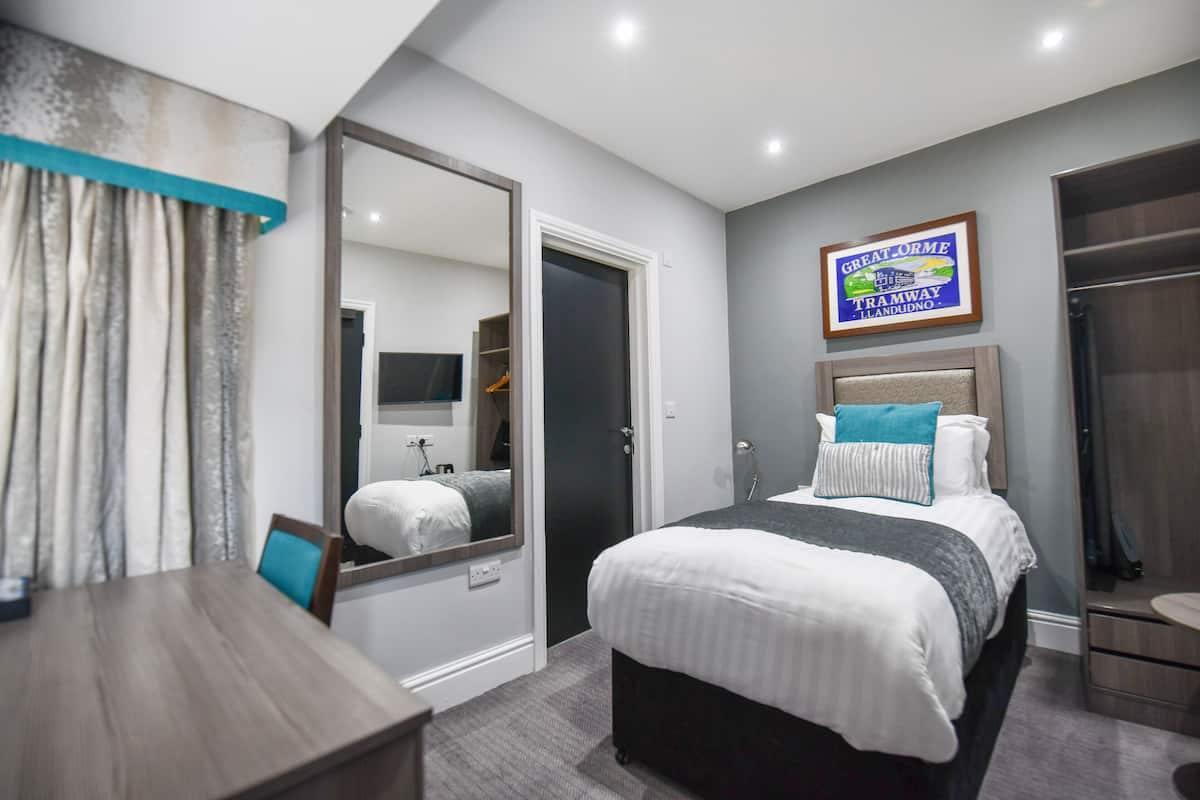 Une chambre d’hôtel moderne avec un grand lit, une table de chevet, un miroir, une armoire et une salle de bain.