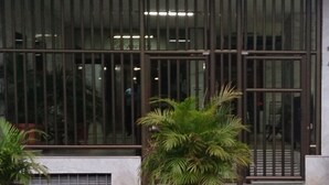 A building facade with large windows and a metal gate. There are two potted plants in front. - Estúdio Praia do Flamengo - 1018 (Rio de Janeiro)