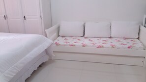 A white bed with a white mattress and a white headboard.