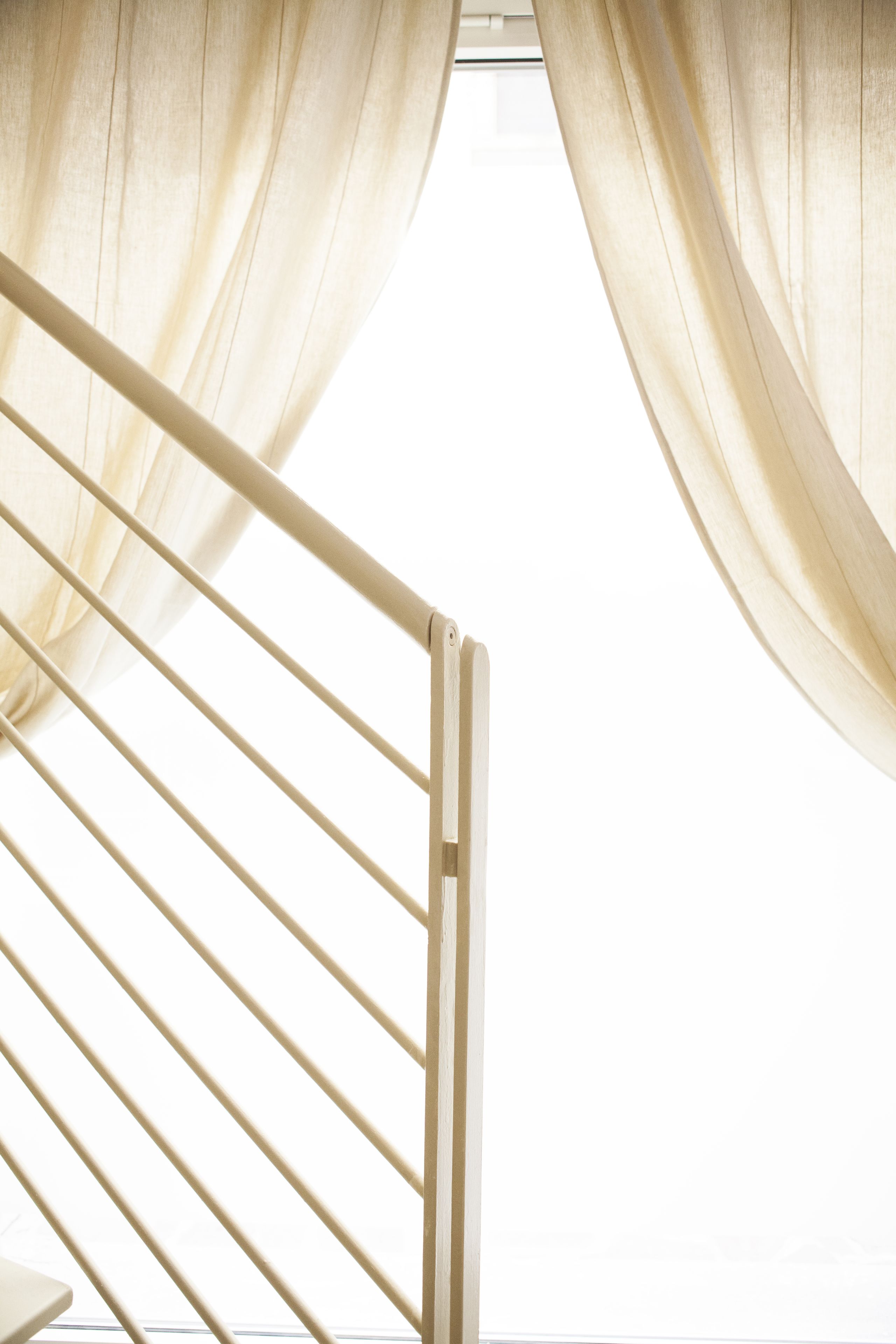 A staircase with a metal railing and sheer curtains.
