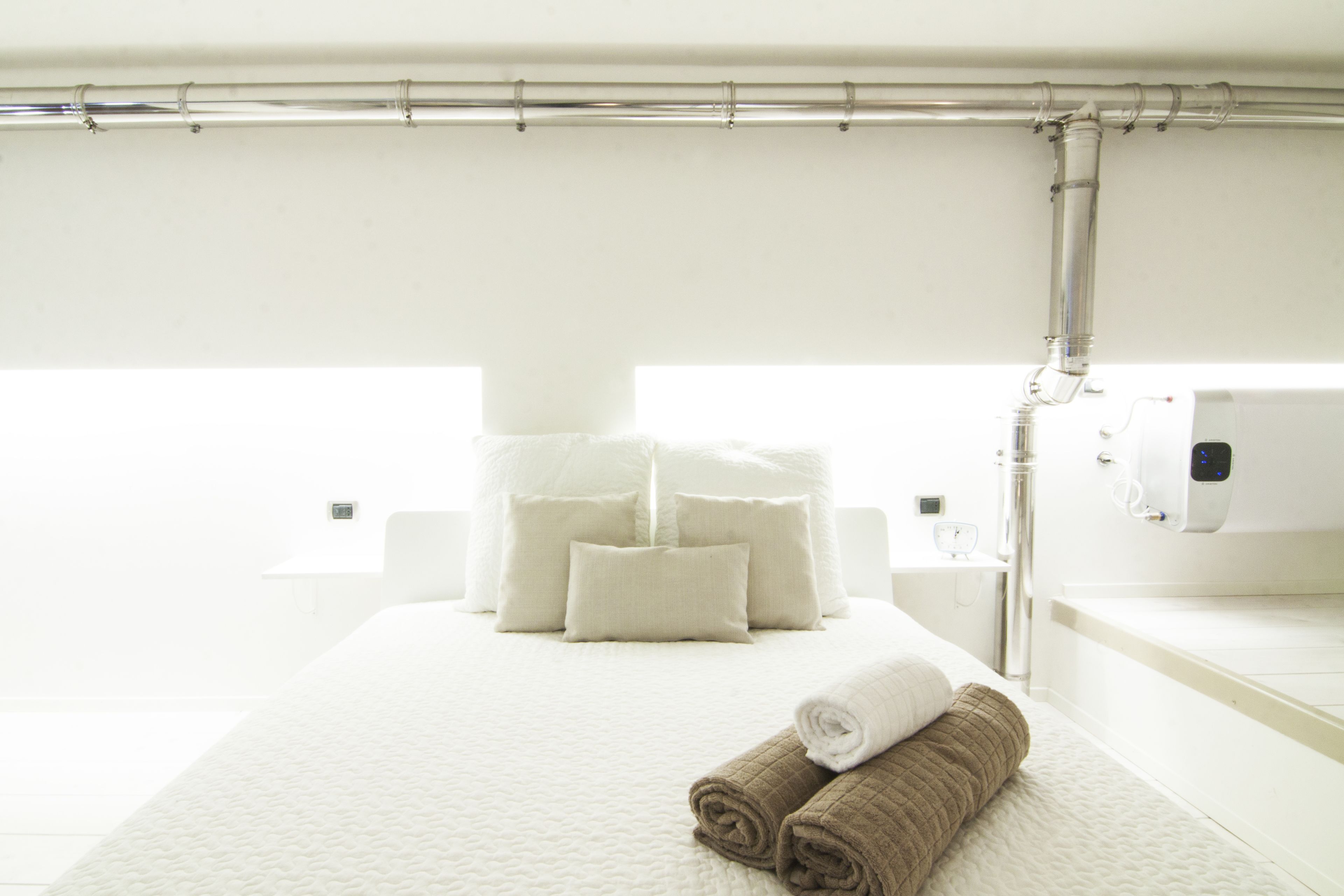Une chambre d’hôtel avec un grand lit, du linge de lit blanc, une salle de bain avec une baignoire et un porte-serviettes.
