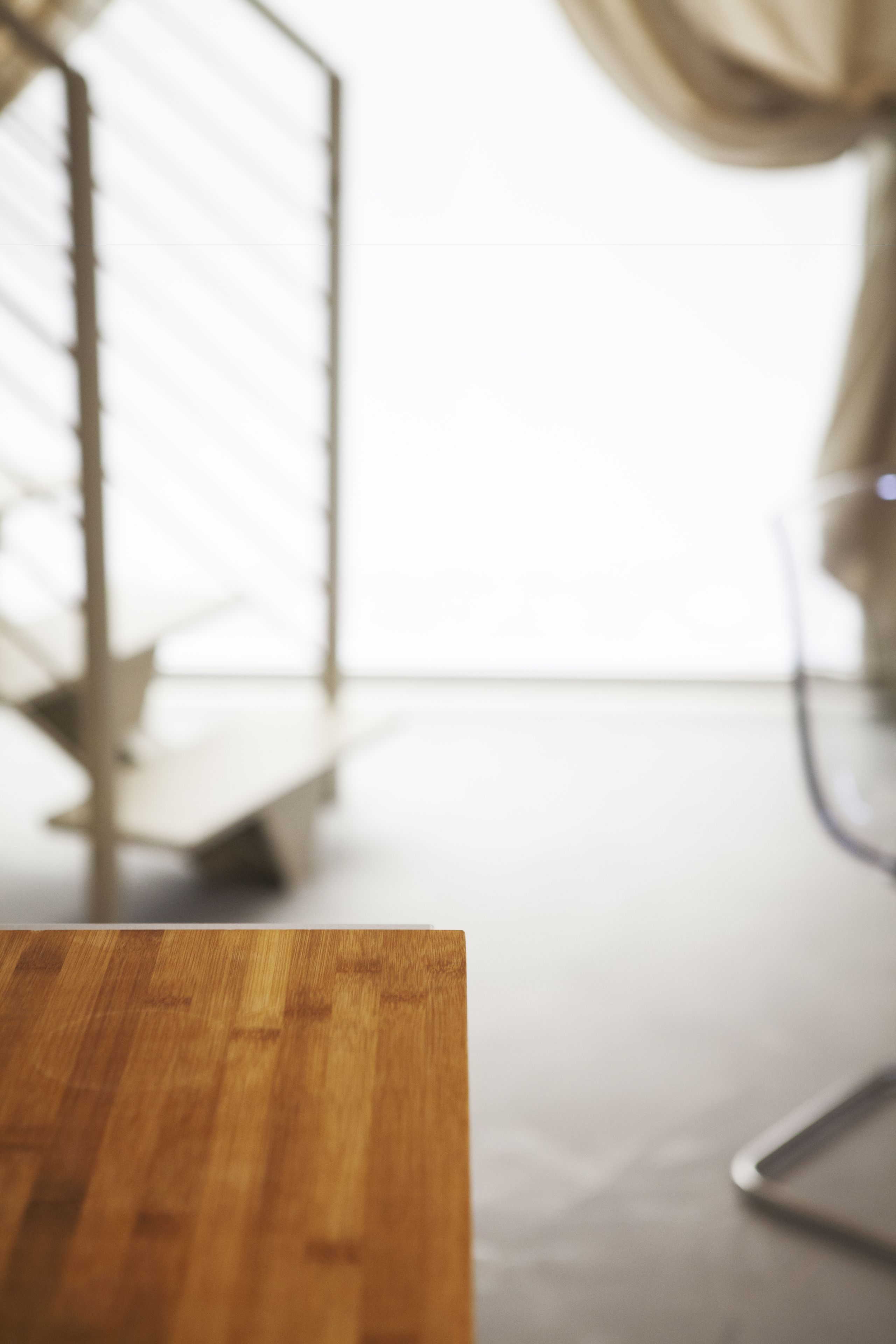 A wooden table in a room with a metal railing and a curtain.
