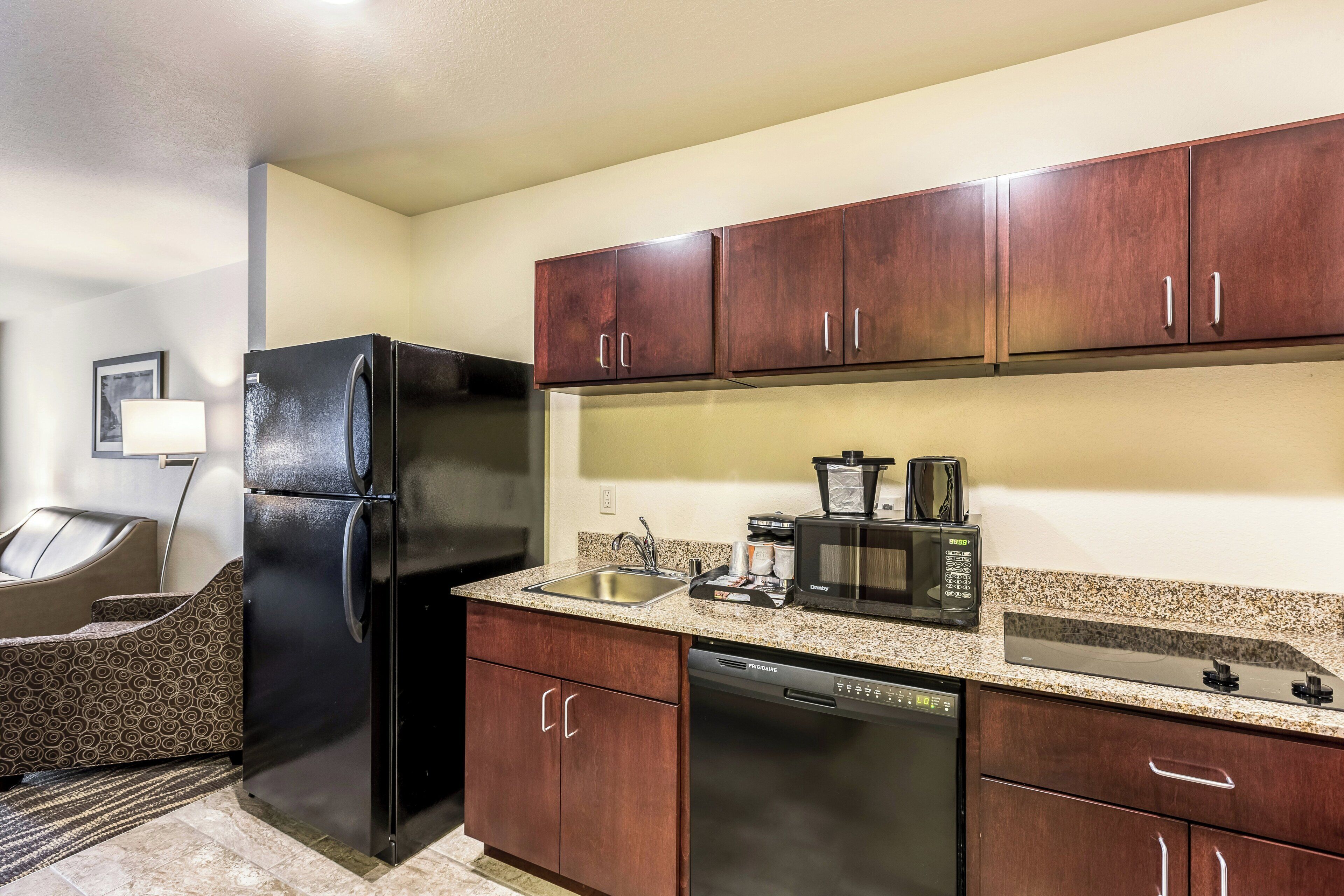 Cocina compacta con refrigerador, microondas, cafetera y lavavajillas.
