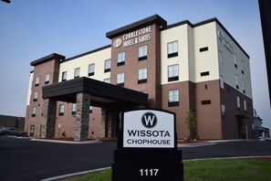 Um hotel com uma placa indicando "Cobbleshoot Hotel & Suites" e "Wissota Chophouse" no número 1117.