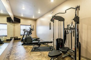 Un gimnasio con equipo de ejercicio, cintas de correr y un banco para pesas.
