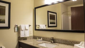 A bathroom with a granite countertop, a sink, a mirror, and a towel rack.