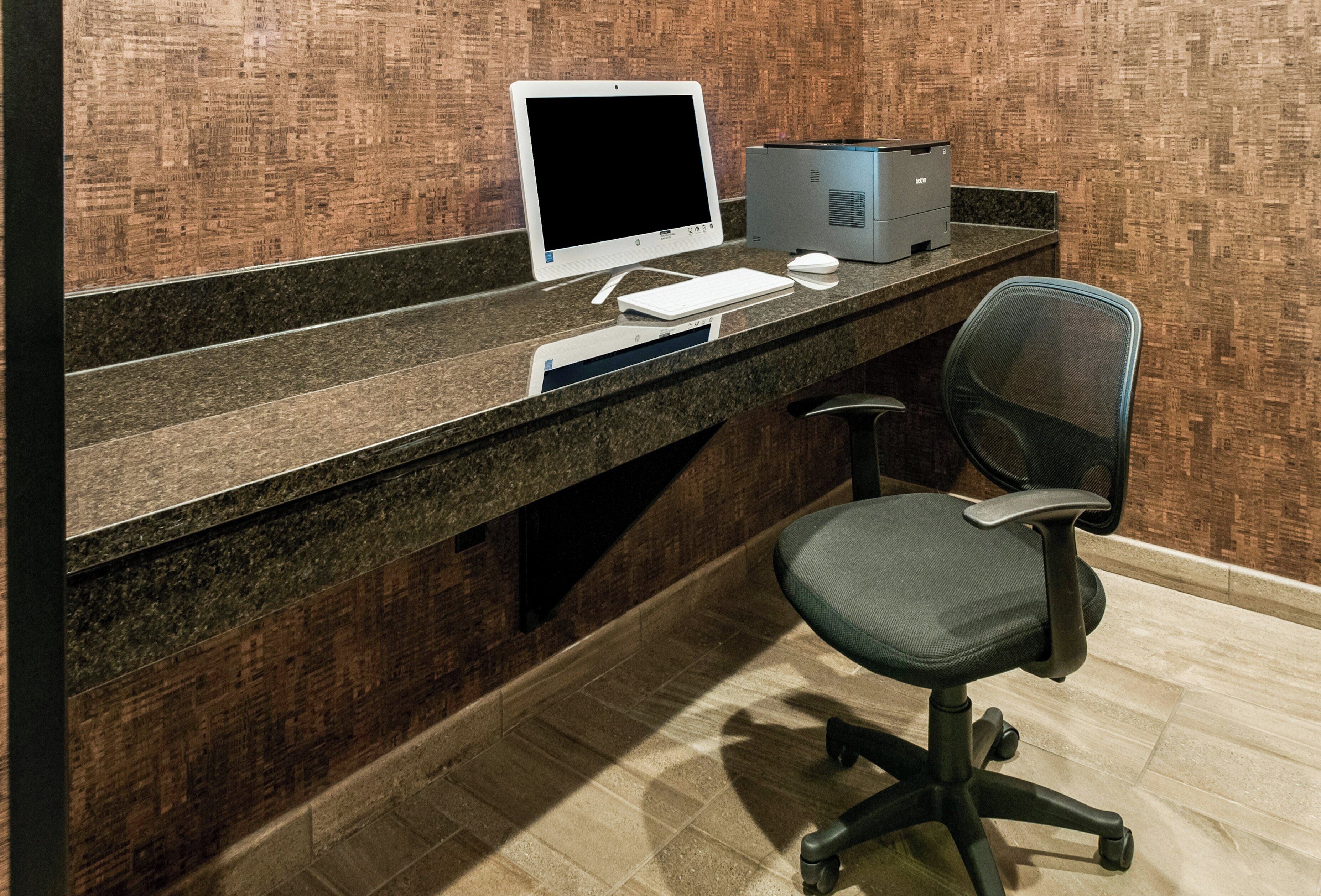 Um espaço de trabalho com computador de mesa, teclado, rato e cadeira de escritório.