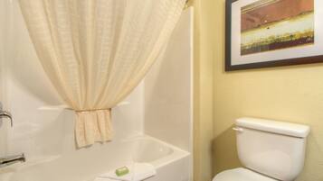 A bathroom with a bathtub, toilet, and a framed picture on the wall.