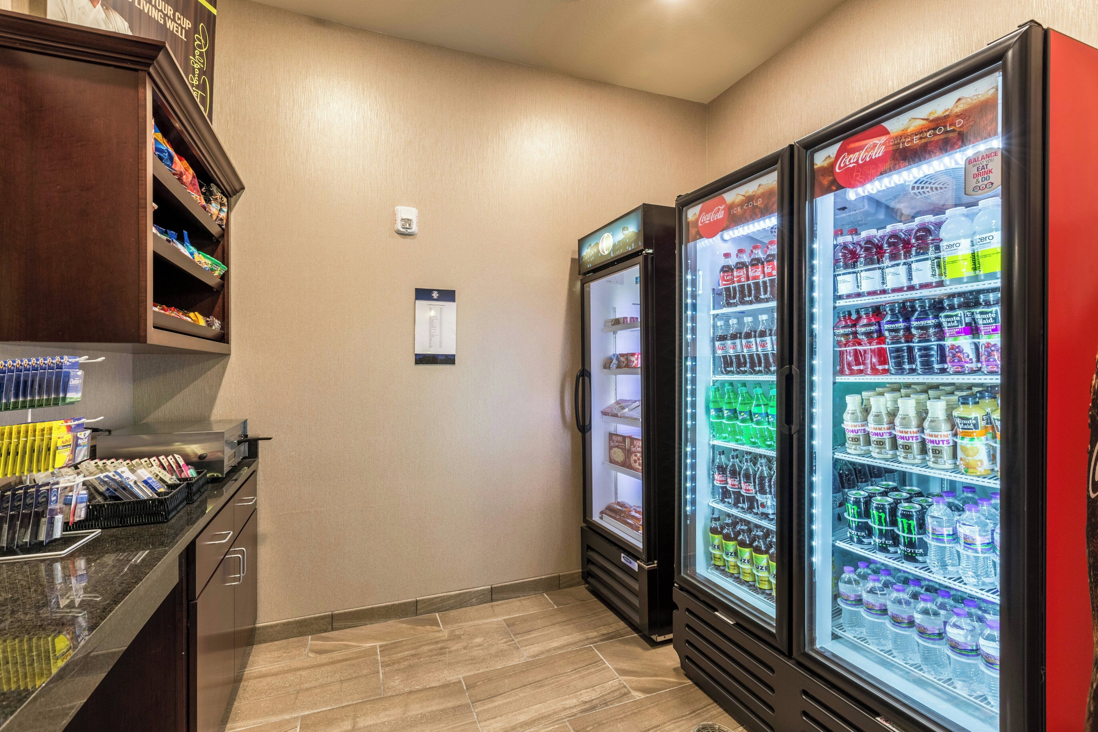 A hotel room with a minibar, a refrigerator stocked with beverages, and a vending machine.