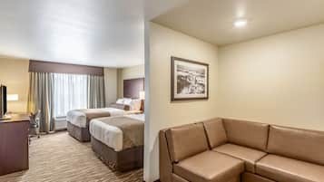 Quarto de hotel com uma cama grande, um sofá, uma escrivaninha e um quadro na parede.