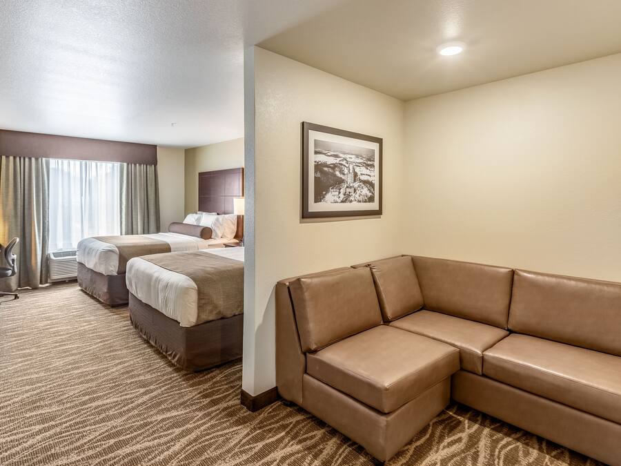 Quarto de hotel com uma cama grande, um sofá, uma escrivaninha e um quadro na parede.