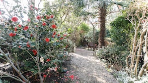 A garden pathway with red flowers and a statue. - Jesmond Hotel (London)
