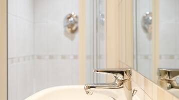 Un baño con grifería cromada, un espejo y paredes de azulejos.