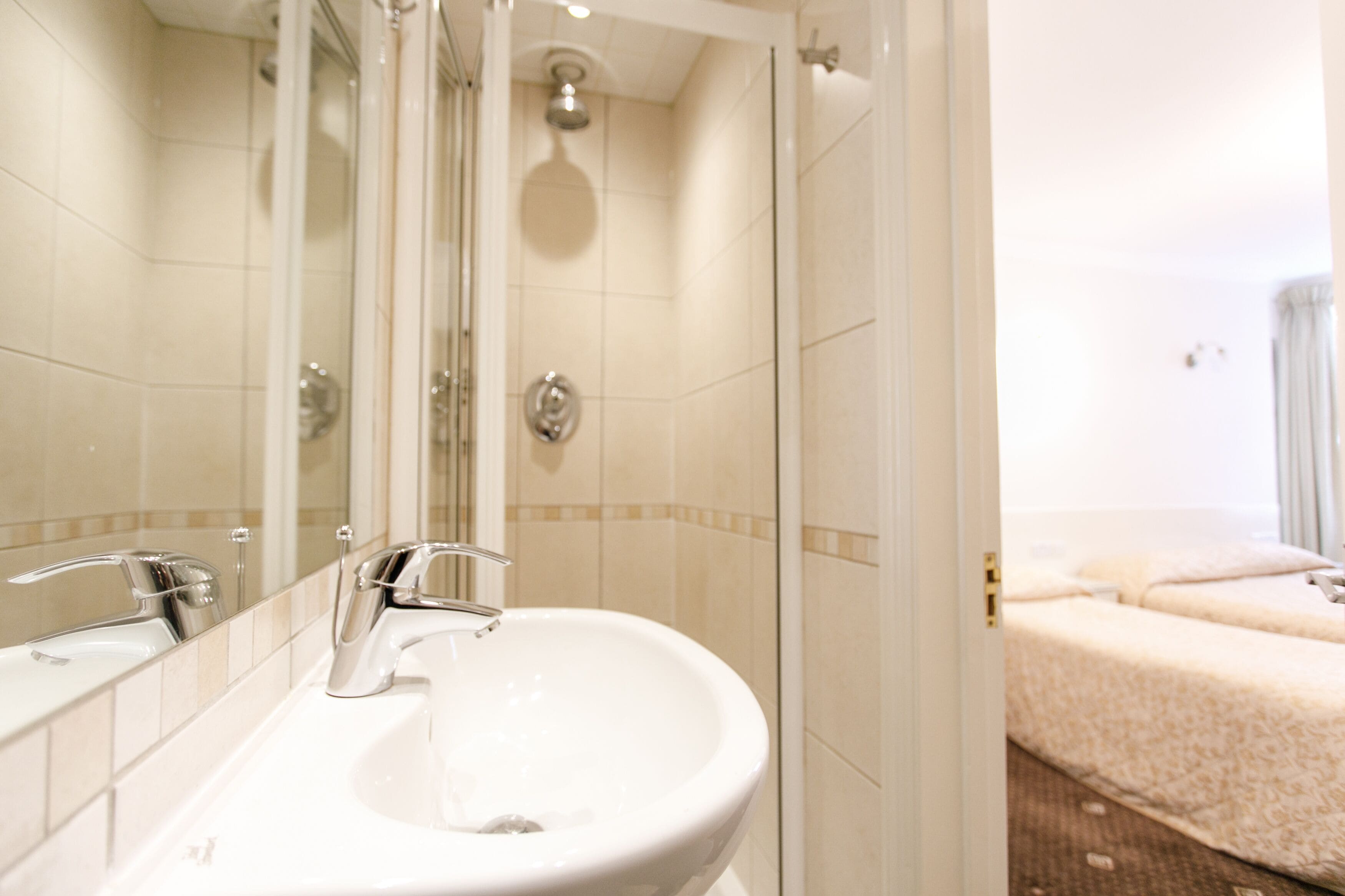 A bathroom with a white sink, two mirrors, and a shower.