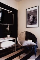 A modern room with a black and white color scheme, featuring a white desk with a plant, a black and white framed picture on the wall, and a black and white striped floor.
