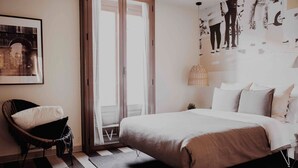 A bedroom with a bed, a chair, a door, and a wall with a poster. - Select Sol (Madrid)