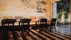 A dining area with wicker chairs, a wooden floor, and a large abstract mural on the wall. - Select Sol (Madrid)