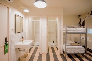 Ein Hotelbad mit Waschbecken, Spiegel, Dusche und einem Stockbett.
