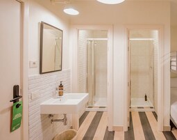 A modern bathroom with a white sink, mirror, and shower.