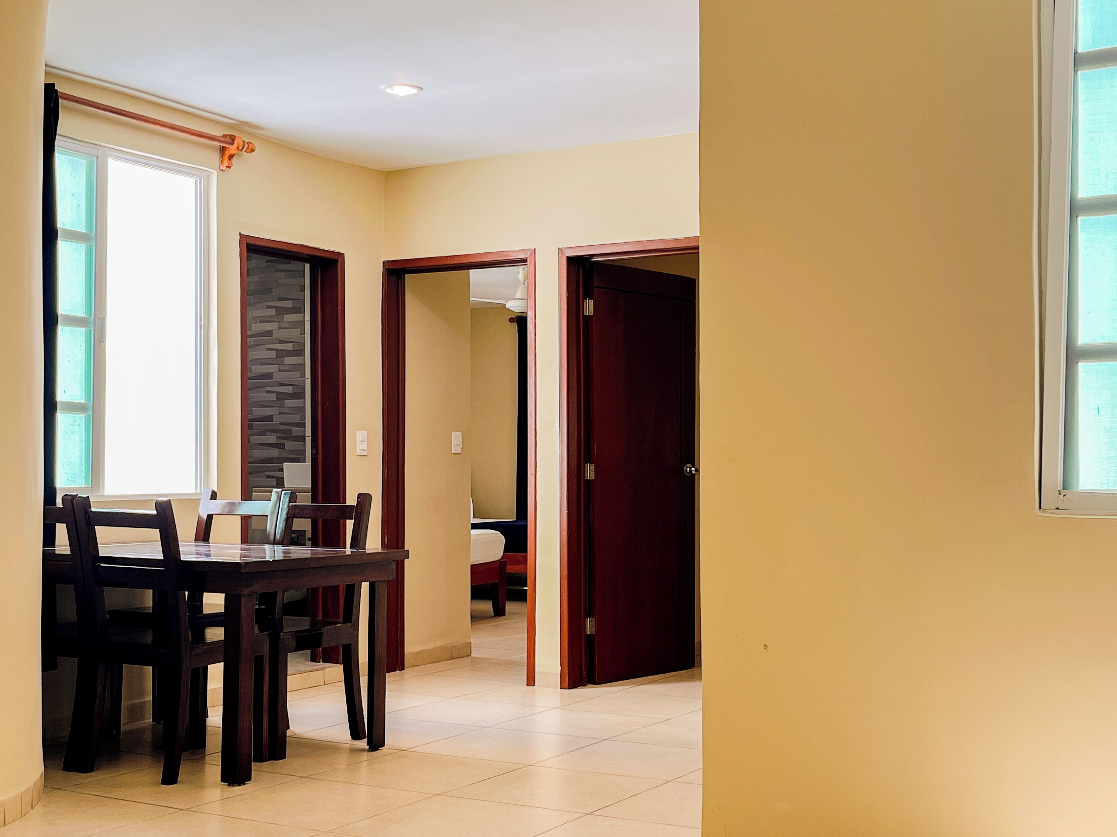 A dining area with a table and chairs, a window, and a door leading to another room.