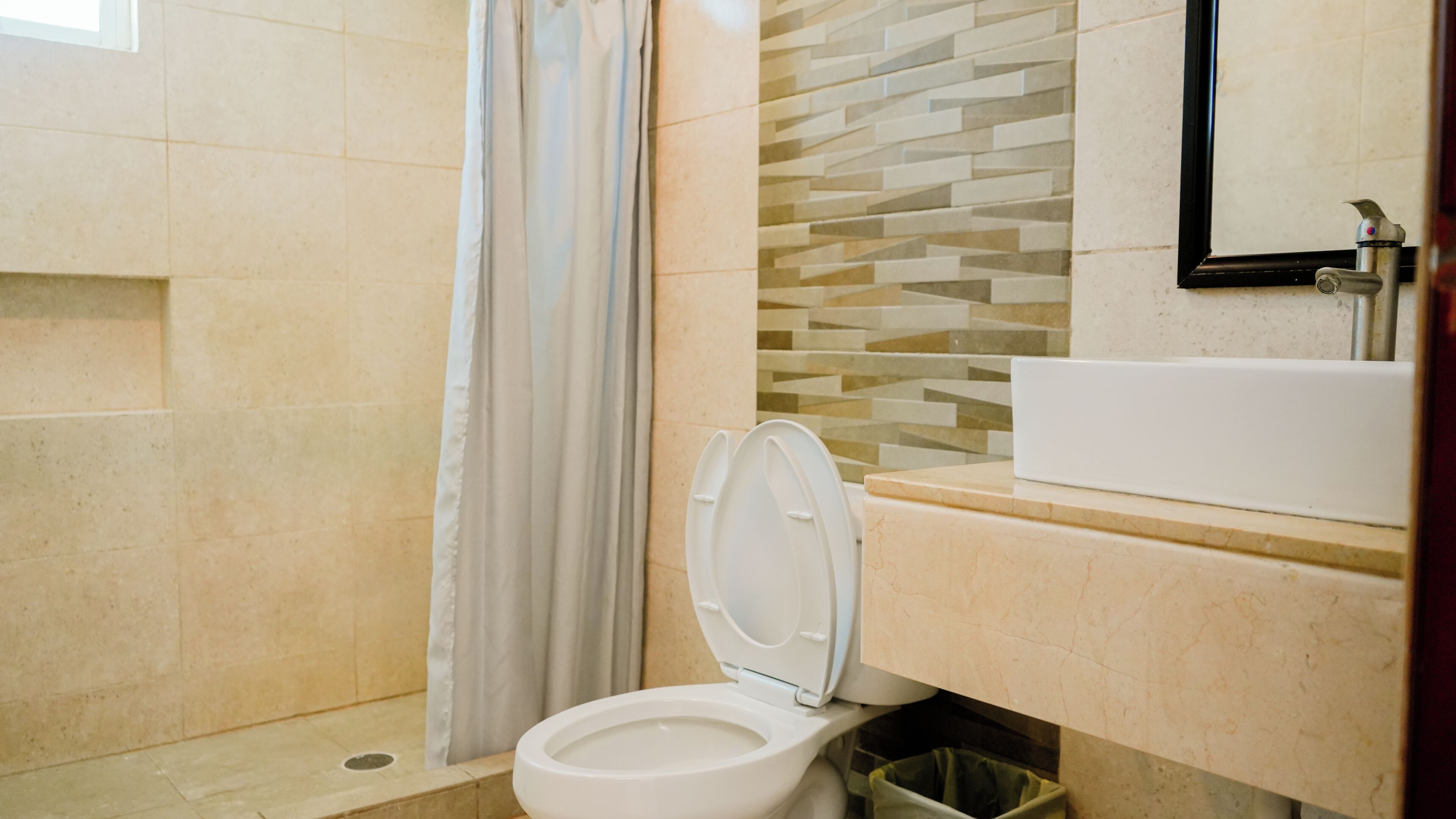 A bathroom with a toilet, a shower, and a sink.