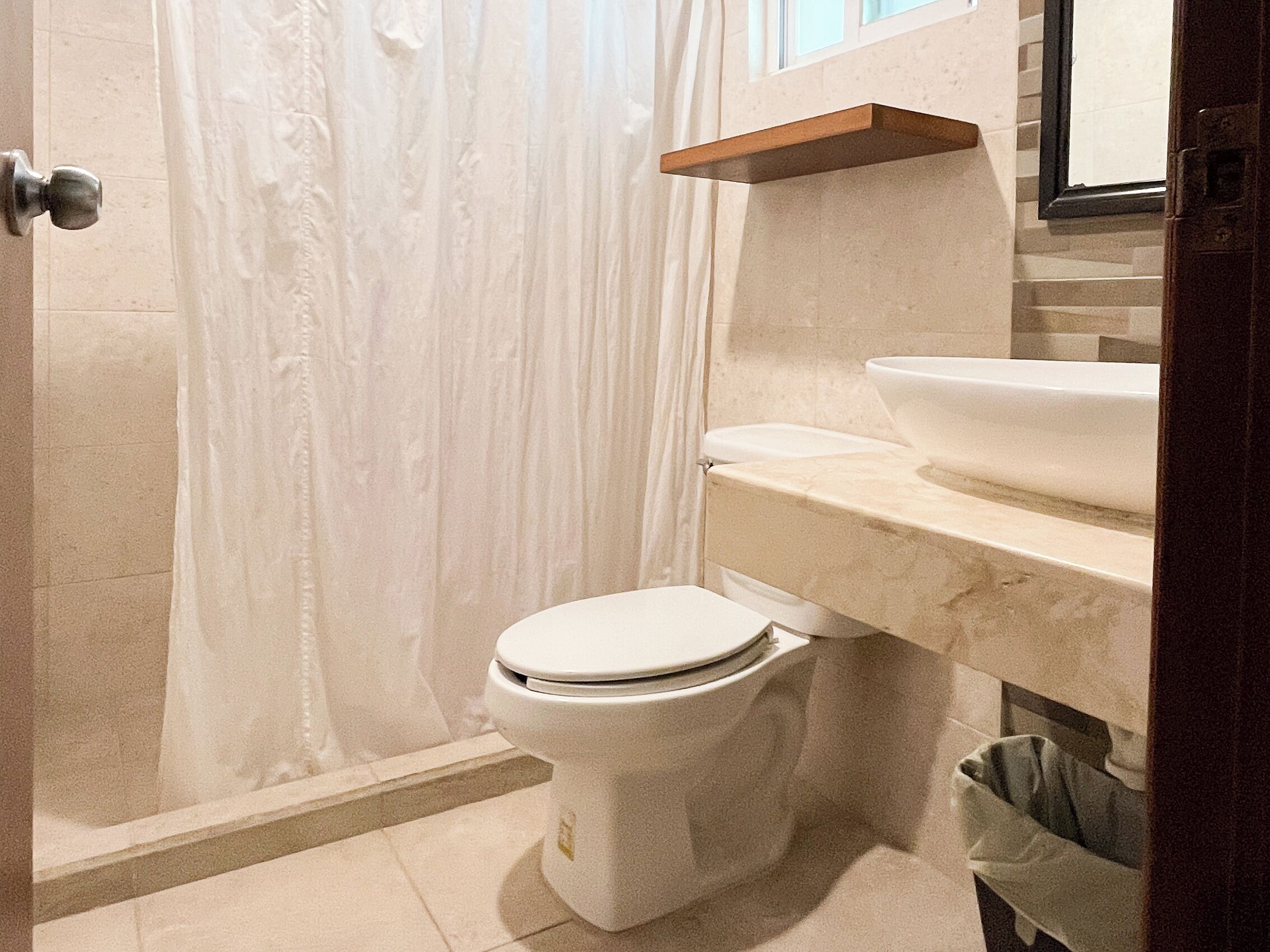 Une salle de bain équipée de toilettes, d’un lavabo, d’un rideau de douche et d’un porte-serviettes.