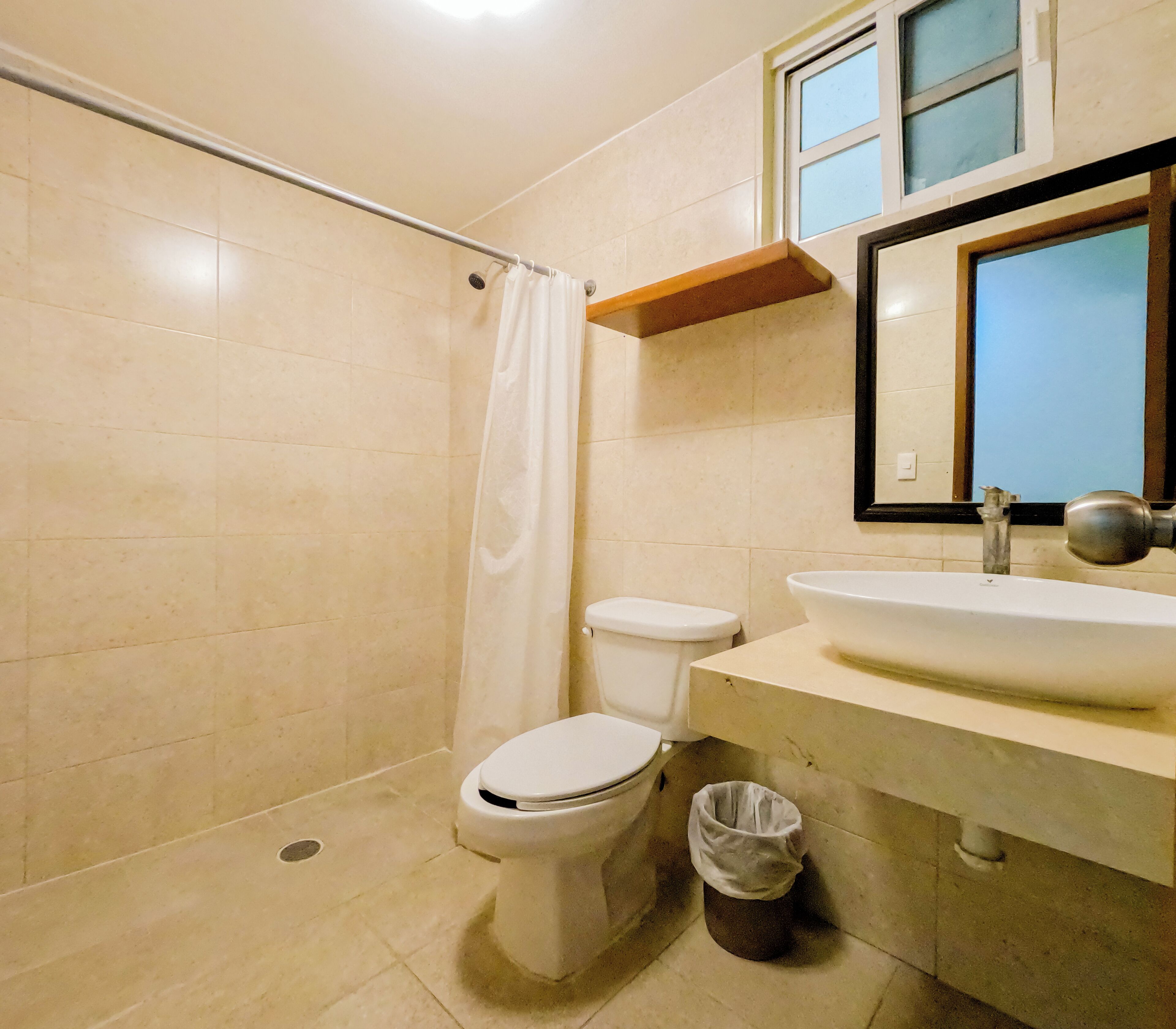 Un baño con ducha, inodoro, lavabo y espejo.