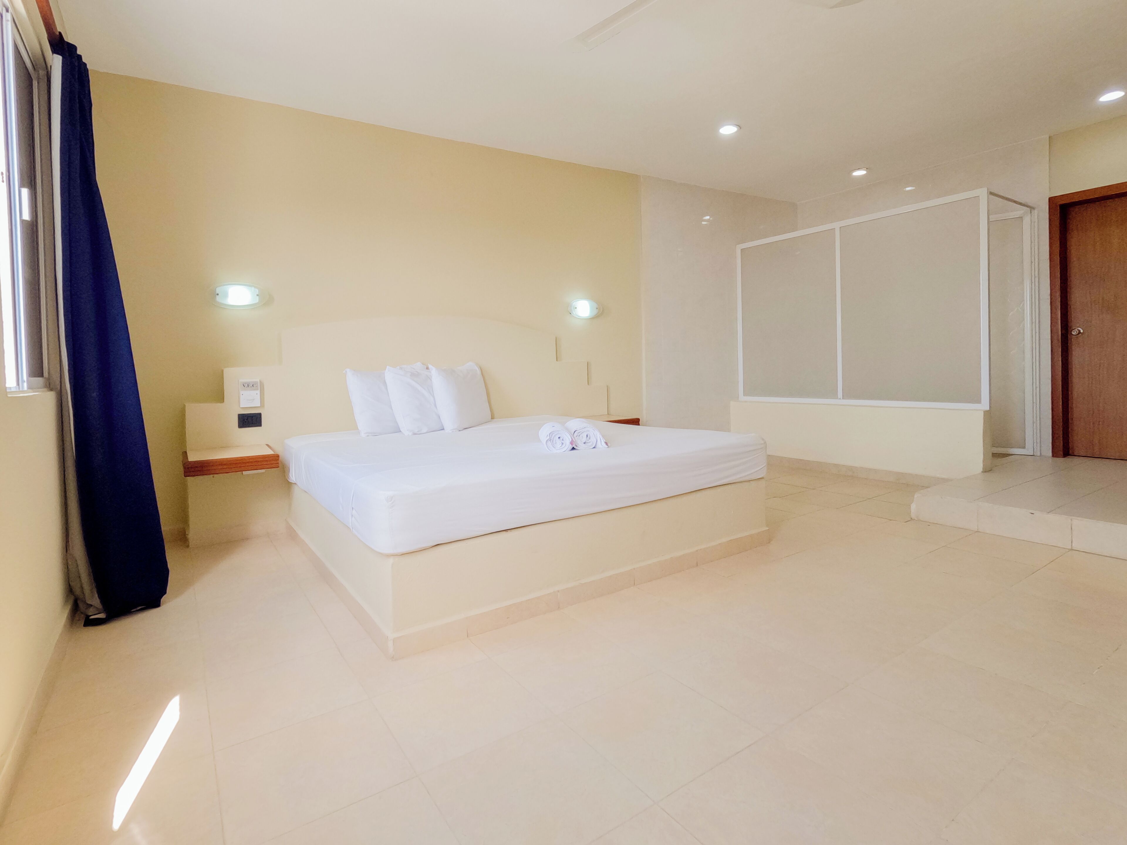 A bedroom with a bed, bedside table, wall-mounted light, and a door.