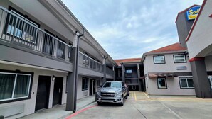 A parking area with a truck, a building with a 'Scott's Inns' sign, and a red star emblem. - Scottish Inns and Suites East Sam Houston Pkwy (Houston)