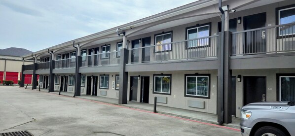 A multi-story hotel with a flat facade, balconies, and a parking area.