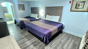A hotel room with two beds, a desk, and a TV. - Scottish Inns and Suites East Sam Houston Pkwy (Houston)