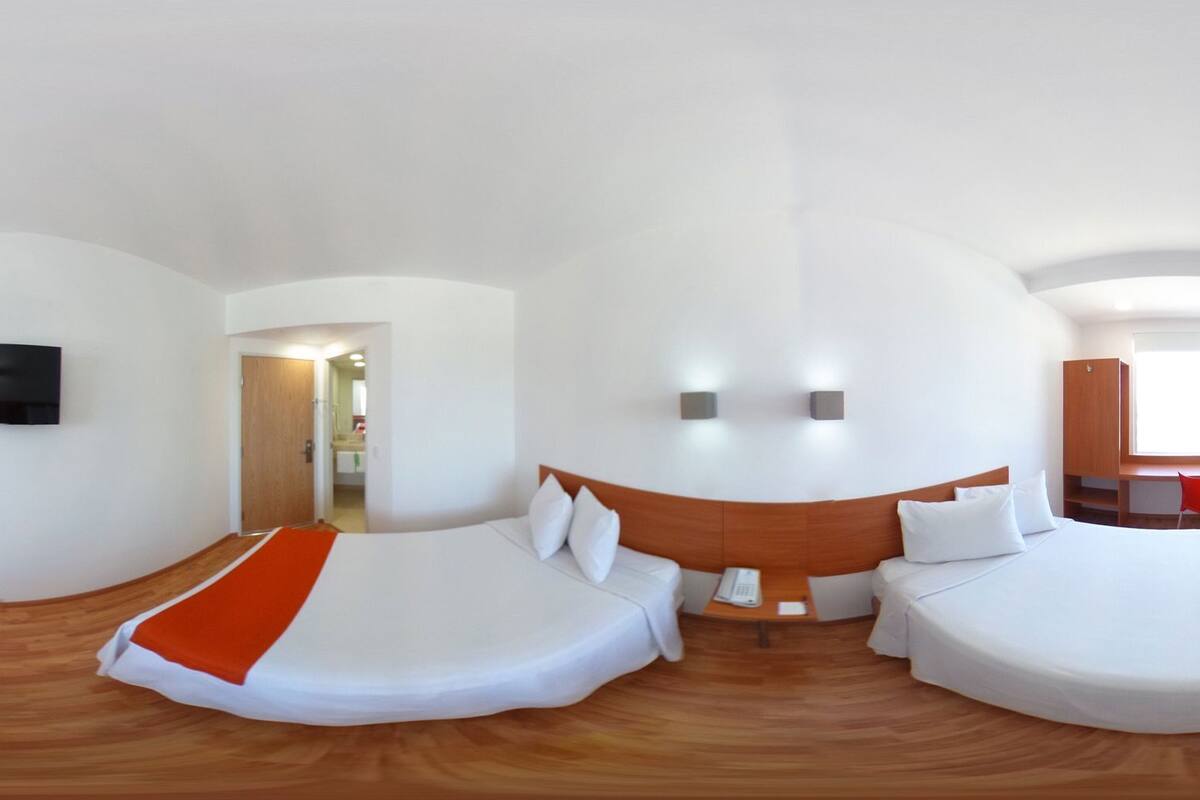 A hotel room with two beds, a TV, a desk, and a phone.