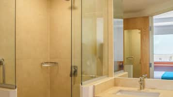 A modern bathroom with a glass-enclosed shower, a large mirror, and a vanity with a towel hanging on the wall.