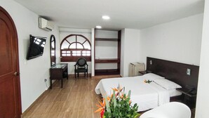 Habitación de hotel con dos camas, un escritorio, una silla, un televisor y una ventana con vistas.