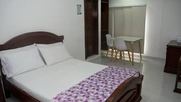 A bedroom with a wooden bed, a desk, and a chair.