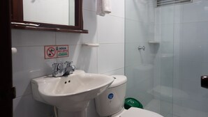 Een badkamer met een wastafel, toilet en douche. Een bordje geeft aan dat het water niet geschikt is om te drinken.