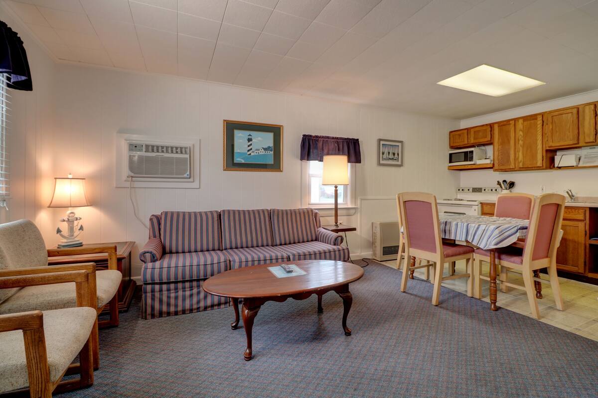 Een woonkamer met een bank, stoelen, een salontafel en een eethoek met tafel en stoelen.