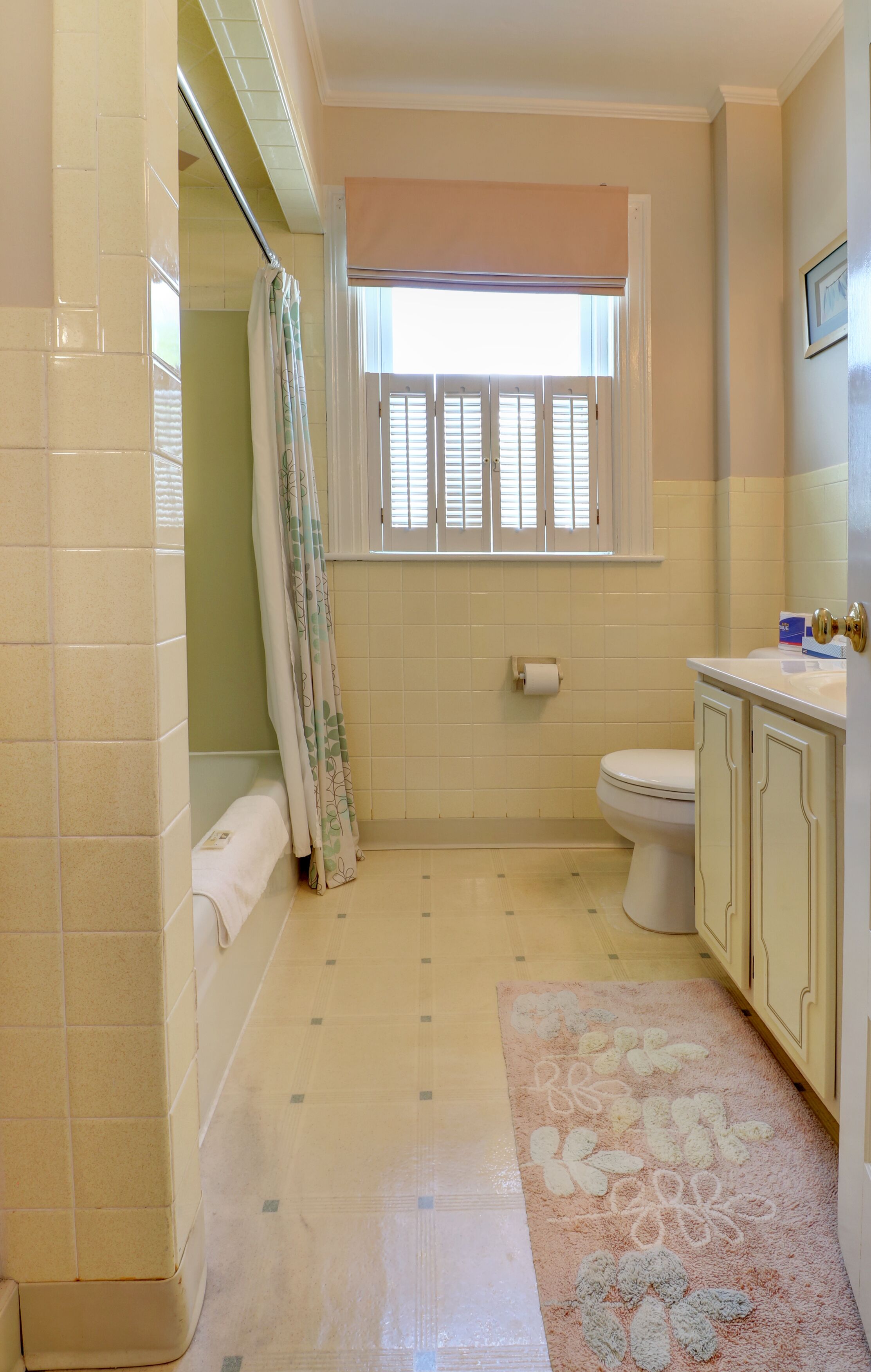 A bathroom with a toilet, a sink, a shower curtain, and a window.