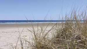 A beach with sand and grass in the foreground, and the ocean in the background. - Carriage House Motel Cottages & Suites (Wells)