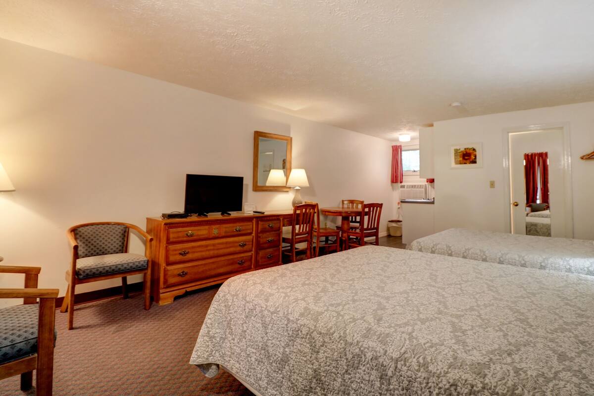 Een hotelkamer met twee bedden, een bureau met televisie, een stoel en een dressoir.