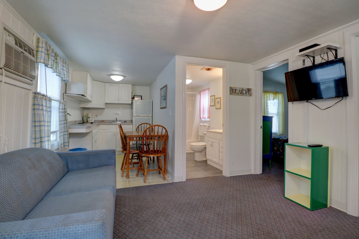 Een knus verblijf met kitchenette, een eethoek, een badkamer en een aan de muur bevestigde televisie.