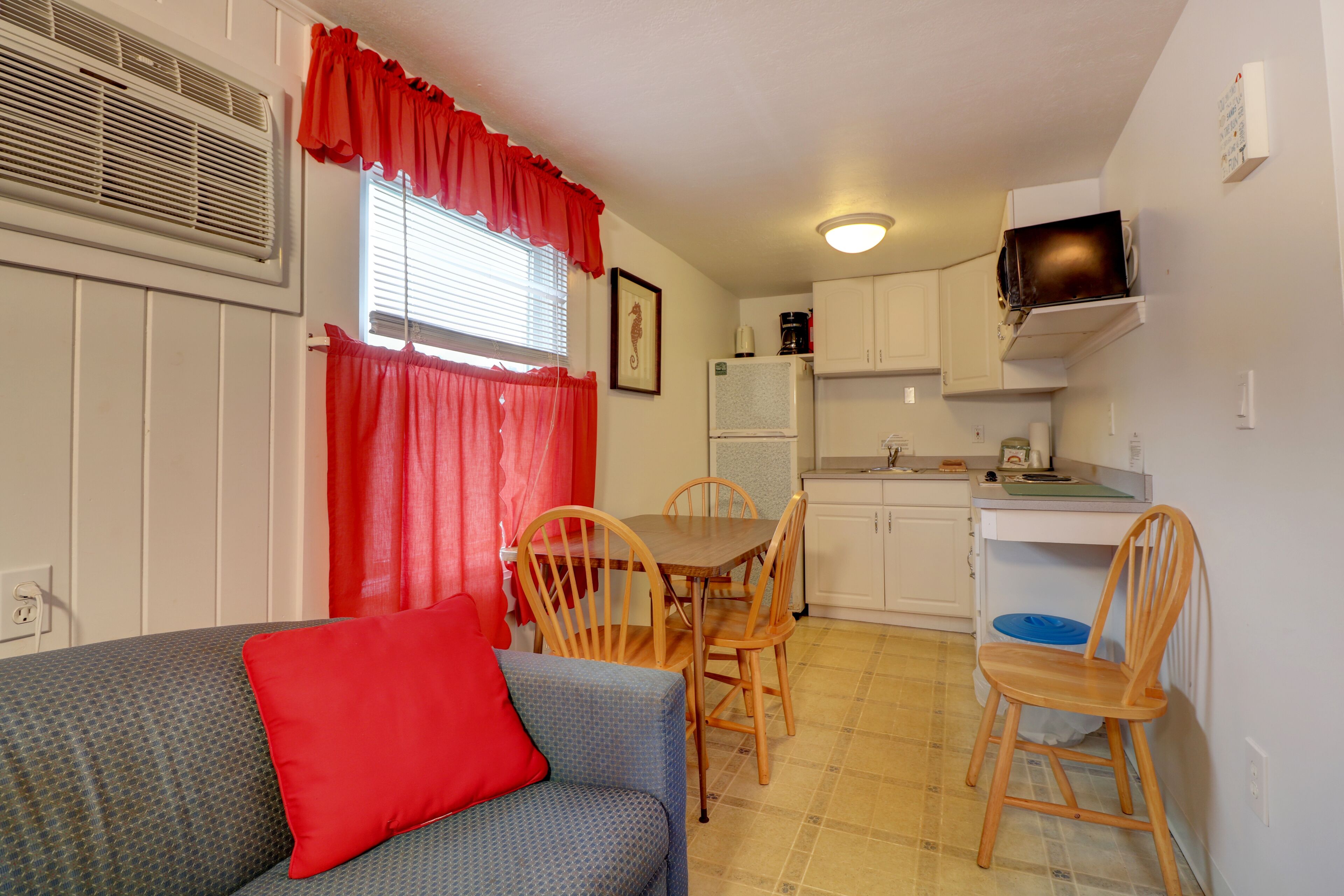 A compact kitchen with a dining table and chairs, a microwave, and a refrigerator.