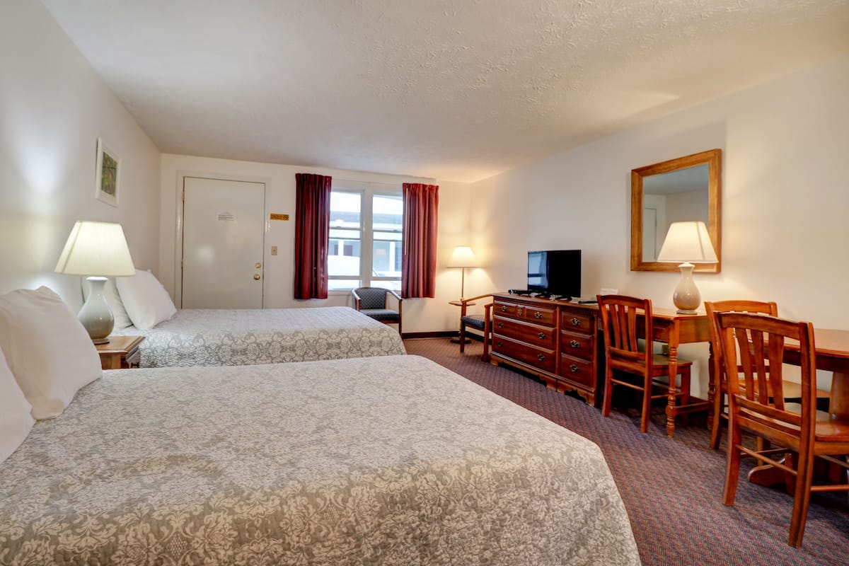 Een hotelkamer met twee bedden, een bureau met een televisie en een stoel.